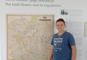 uczeń Filip na tle mapy o likwidacji łódzkiego getta